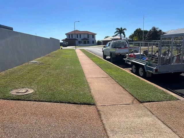 A ute and caged trailer parked at the kerb beside a freshly mown verge