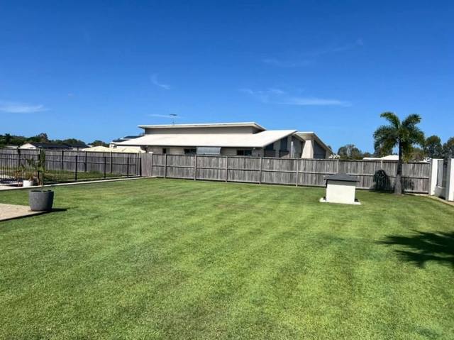 A wide back lawn mown in even stripes behind a home