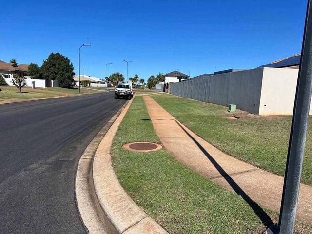 A mown nature strip running along a kerb toward the road