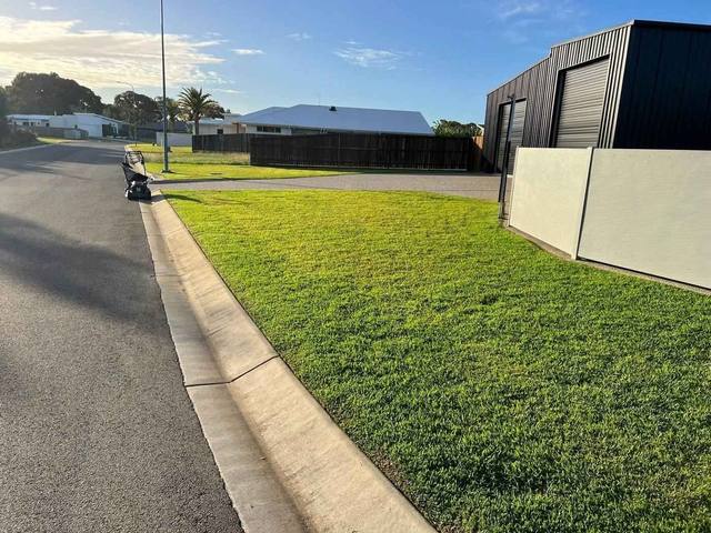 A mown nature strip beside a kerb and footpath
