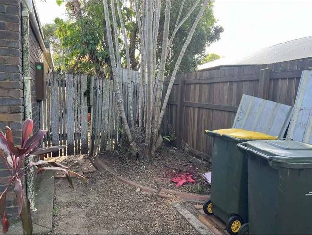 A cleared side yard beside a timber fence with the bins moved back