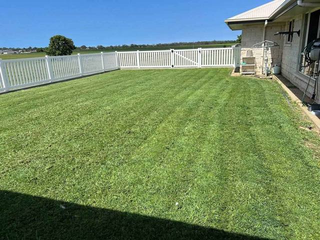 A mown lawn behind a white picket fence