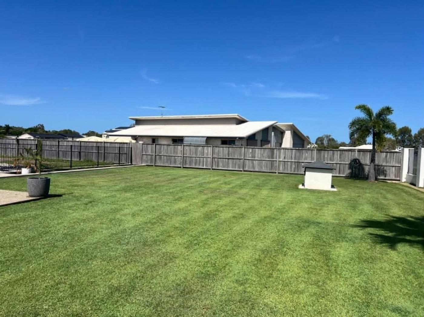 A wide back lawn mown in even stripes behind a home